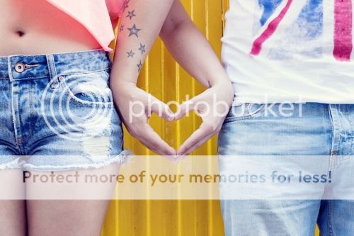 Two people standing next to each other, making a heart shape with their hands